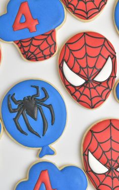 decorated cookies with spiderman faces and numbers are displayed on a white tablecloth background