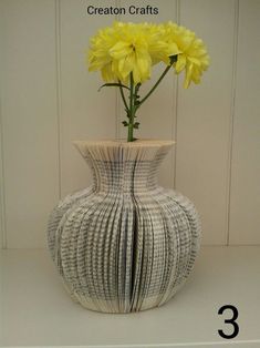 a white vase with yellow flowers in it sitting on a shelf next to a wall