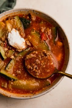 a close up of a bowl of soup with meat and vegetables on the table next to a napkin