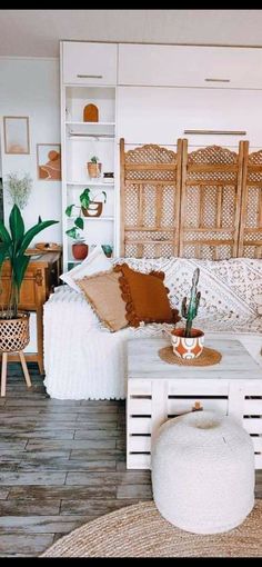 a living room filled with lots of furniture and plants on top of wooden shelves next to a white couch