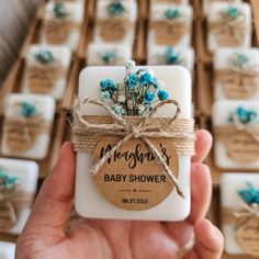 a hand holding a baby shower soap with blue flowers on it and brown twine