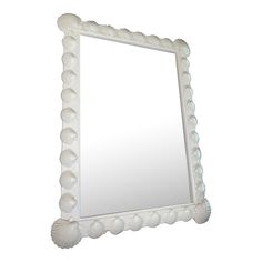 a large white mirror with shells on the frame and bottom edge, in front of a white background