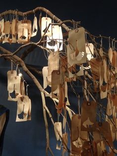 a bunch of paper bags hanging from a tree branch with some lights on top of it