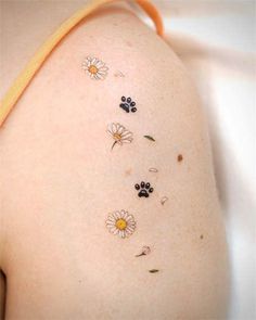 the back of a woman's shoulder with flowers and paw prints on her left side