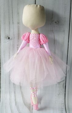 a doll is wearing a pink dress and ballet shoes