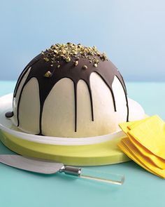 a cake with chocolate and white frosting sitting on a plate next to a knife