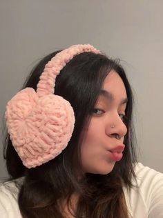 a woman with her tongue out wearing a pink heart shaped ear muffs on top of her head