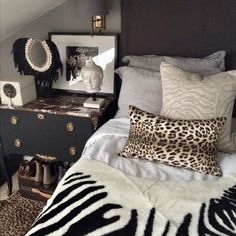 a bedroom with a zebra print blanket on the bed and black dresser next to it