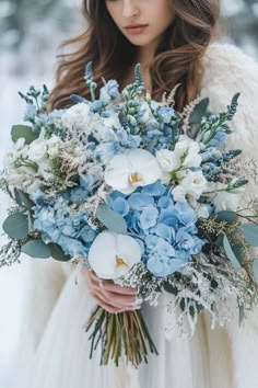 a woman holding a bouquet of blue and white flowers in her hands while wearing a fur coat