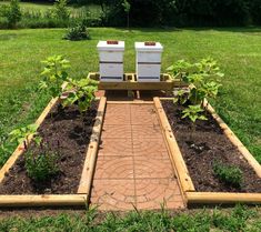 two beehives sitting on top of a garden bed