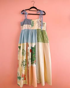 a dress hanging on a hanger against a pink wall