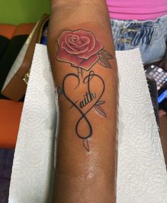 a woman with a rose on her arm and the word faith written in black ink