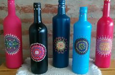 four different colored wine bottles sitting next to each other on a table with a brick wall in the background