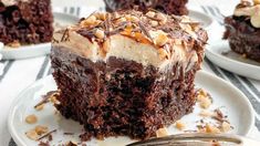 a piece of chocolate cake on a plate with a fork next to it and another slice in the background