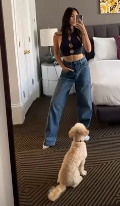 a woman taking a selfie with her dog in front of a bed and mirror