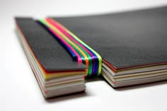 a stack of black notebooks with rainbow ribbons on them