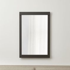 a mirror mounted on the wall above a couch in a room with white walls and furniture