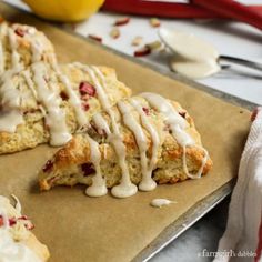 lemon scones with icing and cranberries on a baking sheet