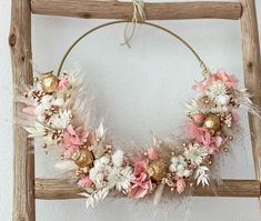 a wreath made out of feathers and flowers on a wooden frame hanging from the wall