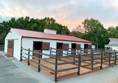 a white barn with brown shutters and a red roof