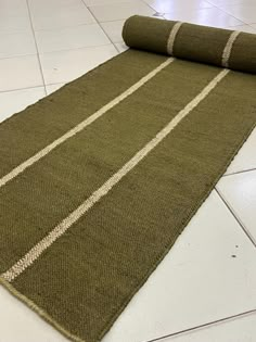 a green rug on the floor with white lines in it and a roll of fabric next to it