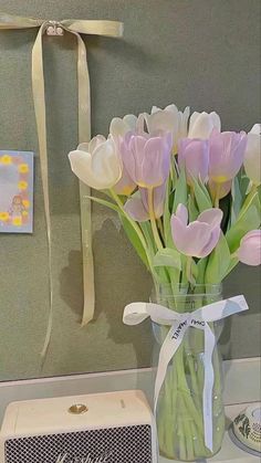 a vase filled with pink tulips sitting on top of a counter next to a radio