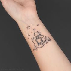 a person's arm with a small tattoo on the wrist and stars around it