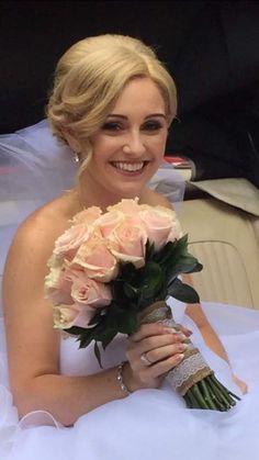 a woman in a wedding dress holding a bouquet of flowers and smiling at the camera