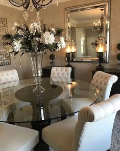 a dining room table with white chairs and a chandelier