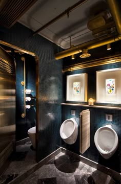 two urinals in a bathroom with blue tiles and gold trim on the walls