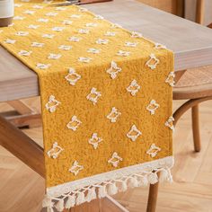 a yellow table runner with white flowers on it