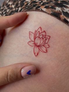 a woman's arm with a red flower tattoo on the back of her stomach