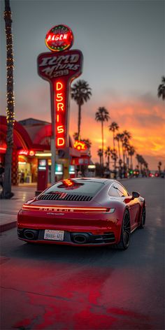 a red sports car parked in front of a fast food restaurant at sunset with palm trees