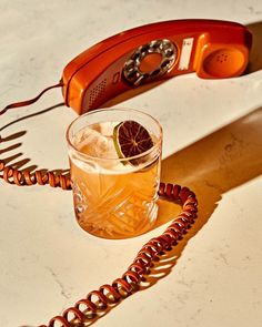 an orange phone sitting on top of a table next to a glass filled with ice