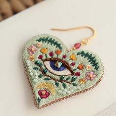 a pair of earrings with an eye in the shape of a heart on a white surface