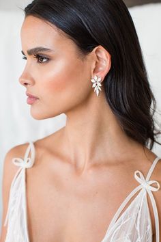 a woman in a white dress wearing earrings with bowknots on the side