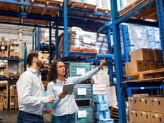 man and woman in warehouse looking at boxes on shelving rack stock photo getty images