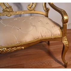 a gold colored chair with a white cushion on top of wooden flooring next to a wall