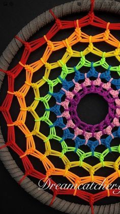 a colorful crochet doily is displayed on a black surface