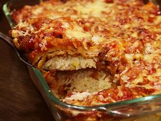 a casserole dish filled with rice and meat covered in sauce, being lifted by a spoon