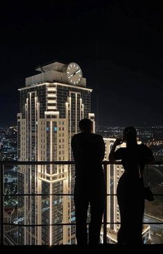 two people standing on top of a building at night