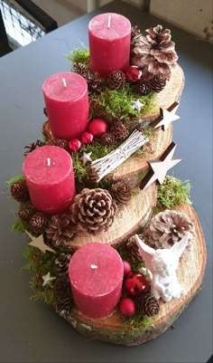 three wooden slices with candles and pinecones on the top are arranged as christmas trees