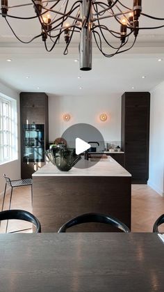 an open kitchen and dining room with chandelier above the island in this modern home