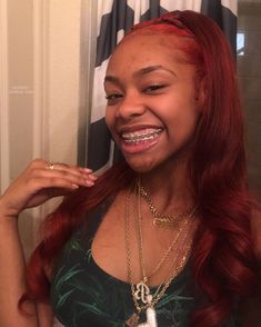 a woman with long red hair smiling and wearing a necklace in front of a shower curtain