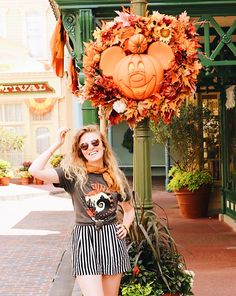 a woman standing next to a pole with pumpkins on it