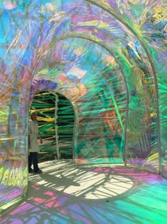 a man standing in front of an art installation made out of plastic tubes and sticks