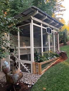 a chicken coop in the middle of a yard with plants growing out of it's sides