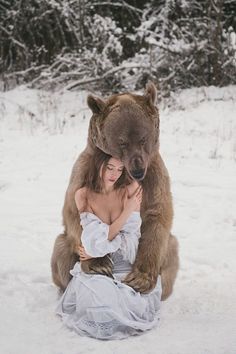 a woman is hugging a bear in the snow