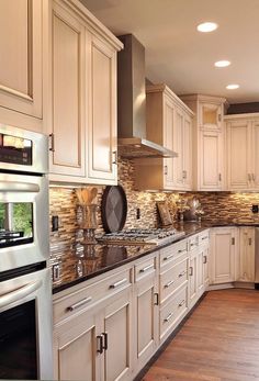 a large kitchen with white cabinets and wood flooring, along with stainless steel appliances