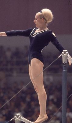 a woman in black leotard standing on top of a pole